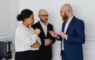 Three People Talking to Each Other While Standing