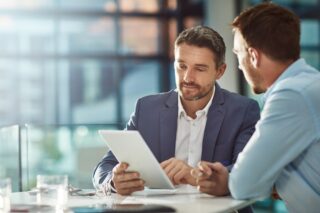 Two Men Going Over Documents In The Office