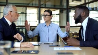 Woman Holding Up Hands To Stop A Conflict Between Two Men