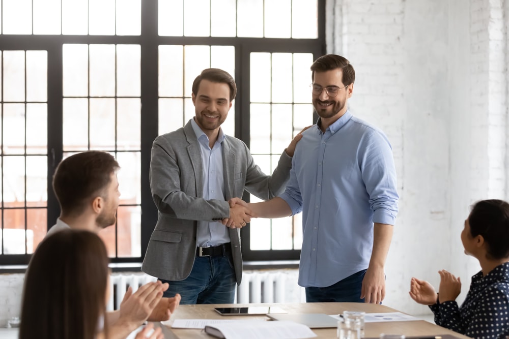 Boss shakes hands with an employee they just had constructive conflict with giving an example to other team members