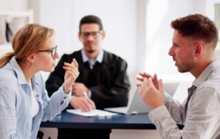 Young couple arguing in front of male judge, contemplating divorce. Family lawyer deals with their dispute, hoping for resolution.