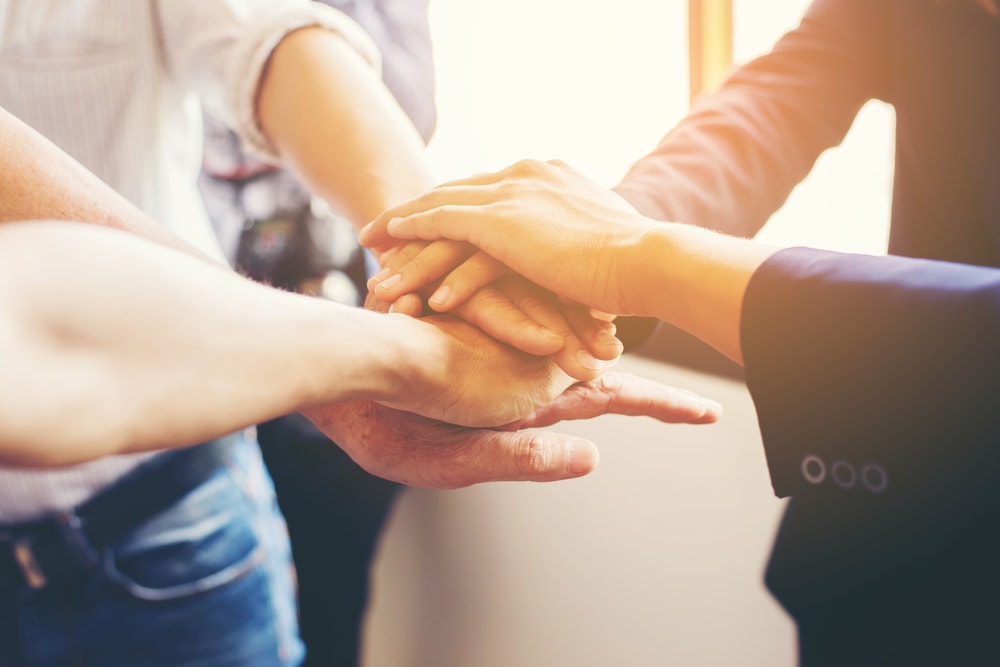  Concept of teamwork: Close-Up of hands business team showing unity with putting their hands together.