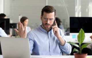 Angry business man talking on phone disputing looking at laptop, stressed frustrated office worker arguing by mobile solving online computer problem with technical support complaining on bad service